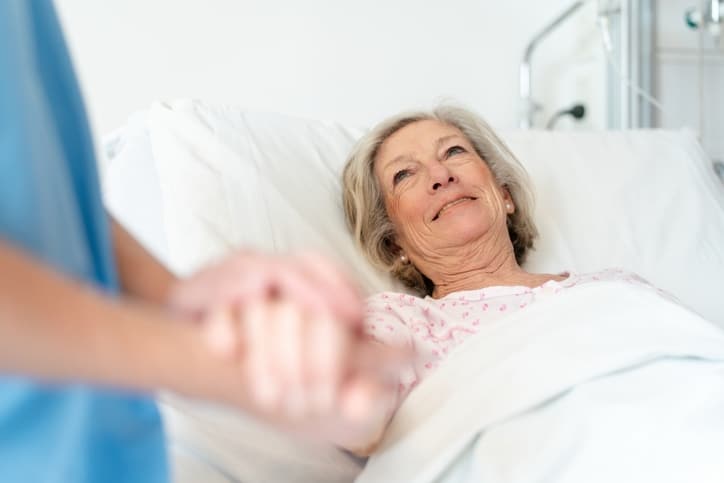 Nurse holding a senior woman's hand during long-term care