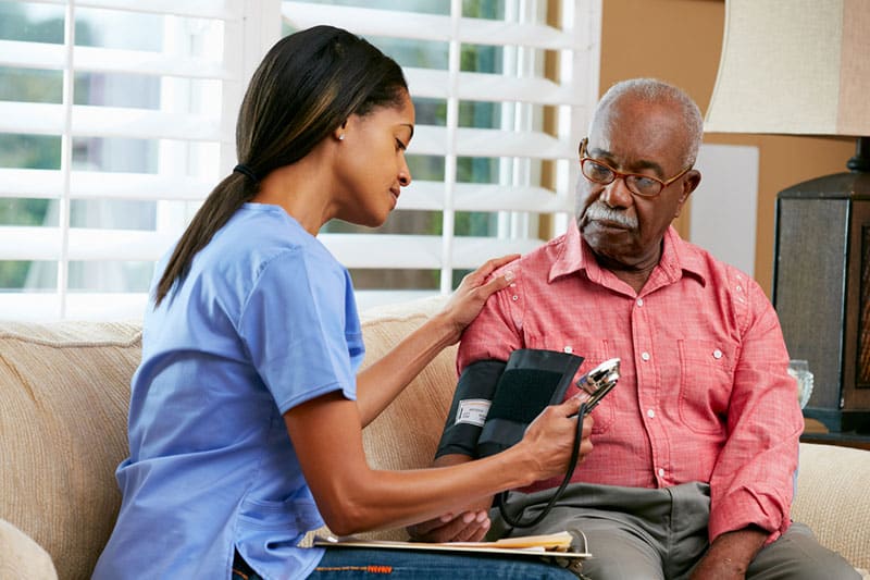Nurse checking a senior man's blood pressure during skilled nursing care