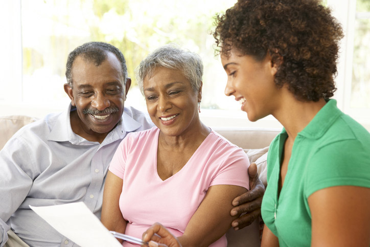 A skilled nursing facility worker in Shreveport reviews a financial document with a senior couple