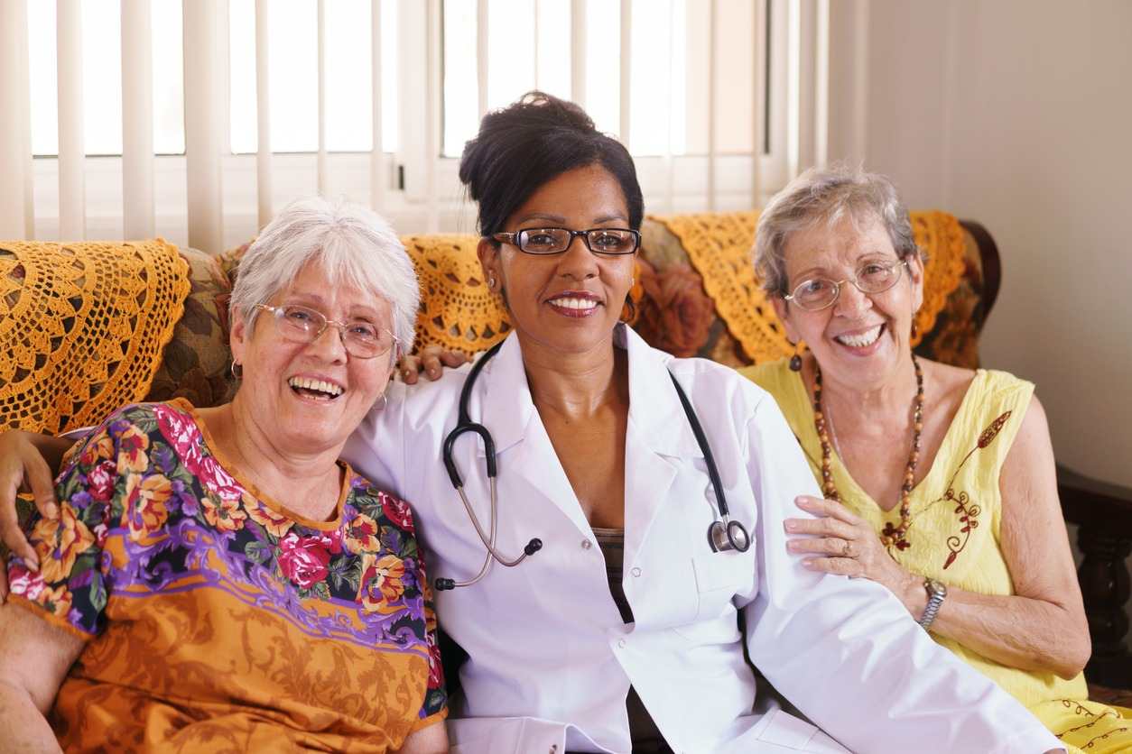 A woman with a stethoscope sits beside two older women, discussing health in Shreveport, LA
