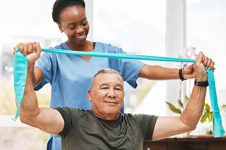 A skilled nursing physical therapist helps a senior man use a resistance band in Shreveport
